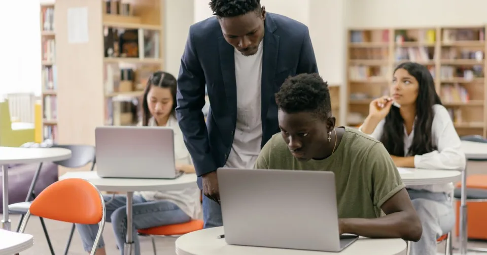 Des collégiens utilisant une tablette avec un enseignant en classe